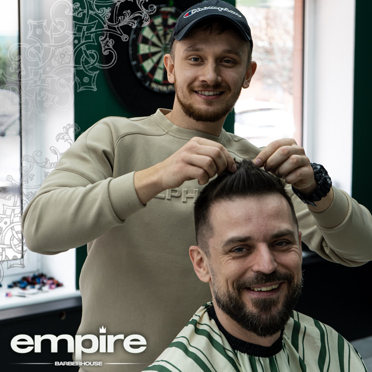 Uśmiechnięty barber poprawia fryzurę zadowolonemu klientowi na fotelu.