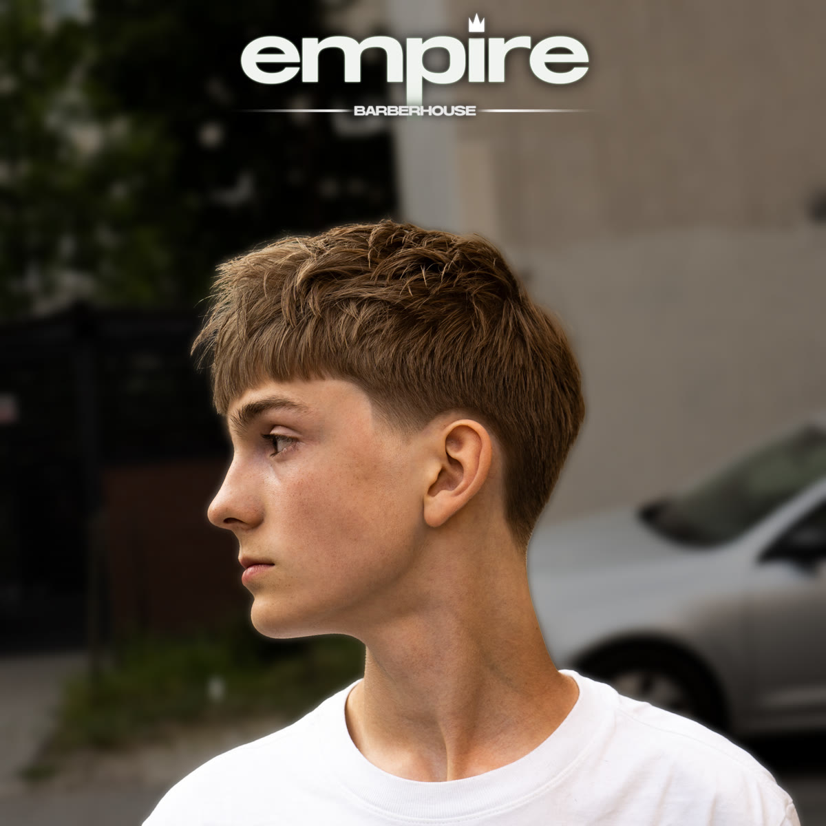 Cropped fringe z teksturowaną górą — profil młodego klienta po strzyżeniu, w tle ulica.