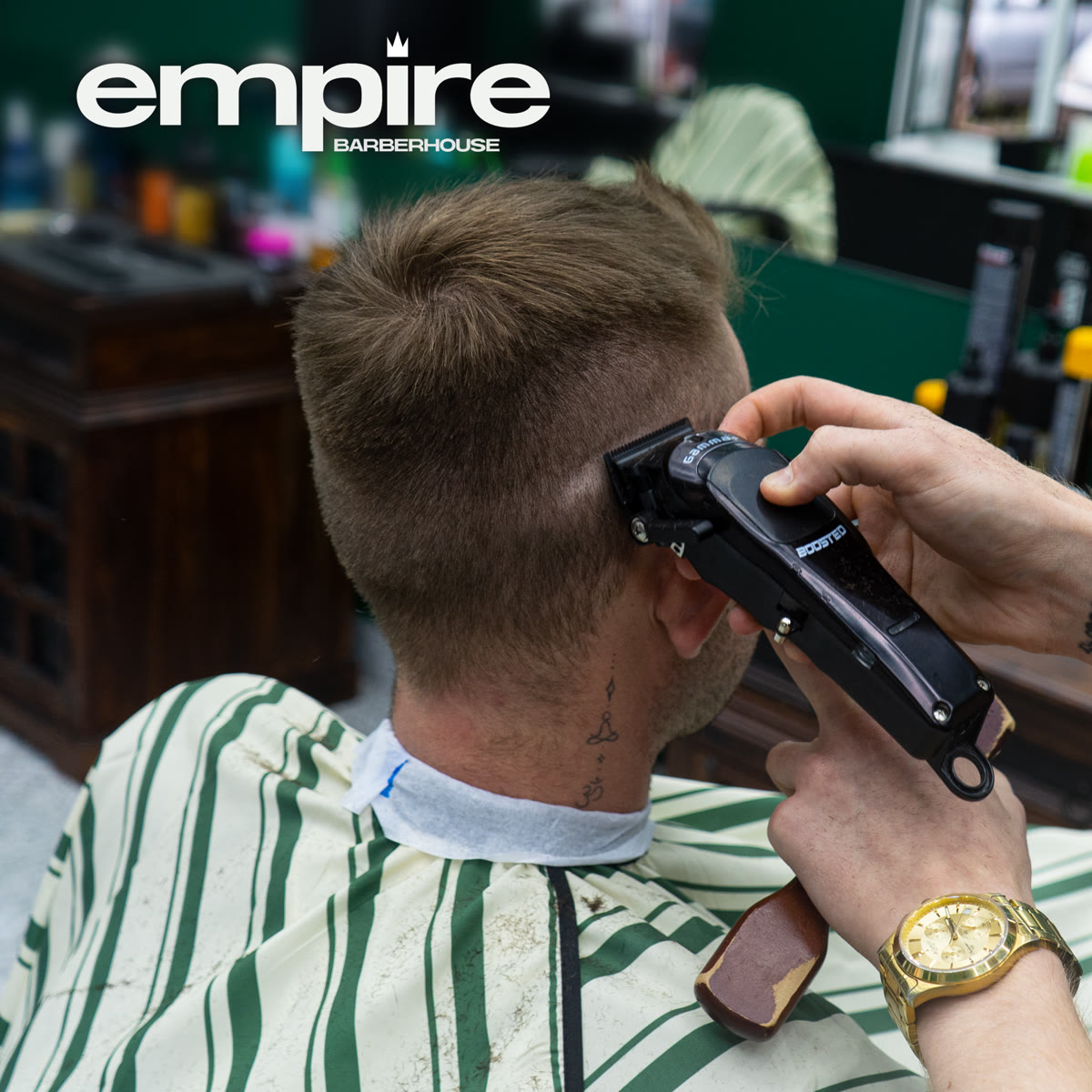 Barber prowadzi maszynkę po skroni klienta — praca nad fade'em z bliska.
